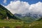 view of green grass meadow with houses and buildings and mountains on Ð’Â background, Ushguli,